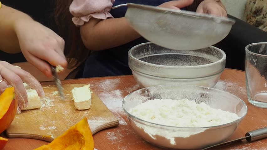 Mother And Daughter Are Making Dough For Thanksgiving Pie. put the dough in a mold for a thanksgiving pumpkin pie. Making Pumpkin pie for Thanksgiving Day. Seasonal traditional autumn festive cake.