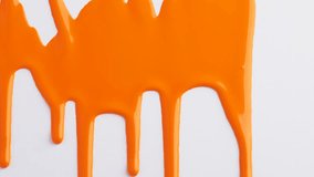 Liquid drops of orange paint color flowing on the white surface. Macro shot of orange paint dripping on the white canvas with copy space. Abstract art. - Powered by Shutterstock - Get 15% off with code: PIKWIZARD15