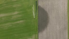 Top down drone footage of an irrigation system misting a field with water on a sunny day