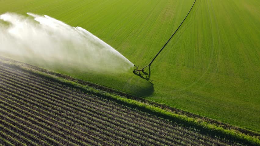 Drone footage of an irrigation system misting a field with water on a sunny day