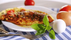 Stuffed omelette with tomatoes on a light wooden background.