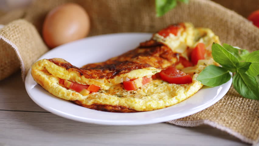 Dried spices are sprinkled on an omelet with tomatoes.