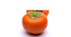 Video of a halved persimmon turned in a white background.