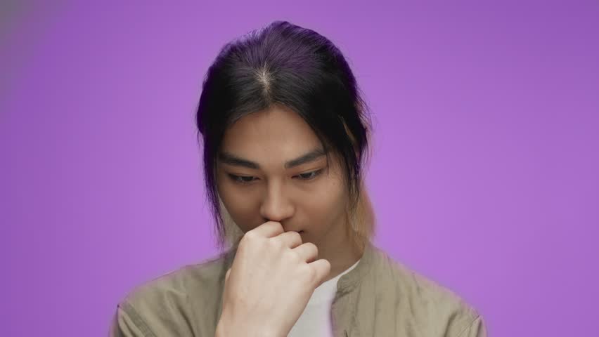Portrait of Young Korean Man Looking at Camera in Colorful Studio Shot. Adult Japanese Boy from Asia Isolated Alone on Purple Background Closeup. Asian 20s Person Raising Head Touching Face by Hand 4k Royalty-Free Stock Footage #1108305839