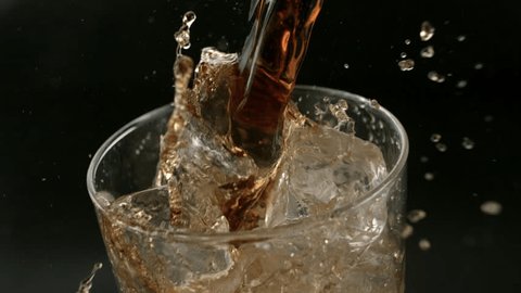 Super Slow Motion Shot of Soda or Soft Drink is pouring along side with Ice Cubes against Black Background, Camera move from Top to side view at 1456fps in ProRes422 Adlı Stok Video