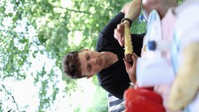 lad in black football shirt eating fried boiled corn outdoors in camping. salt corn. vertical video