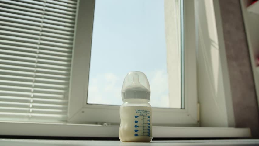 Stirring and shaking a bottle of milk baby food against the background of a window. Preparing infant formula. Copy space for text Royalty-Free Stock Footage #1108314927