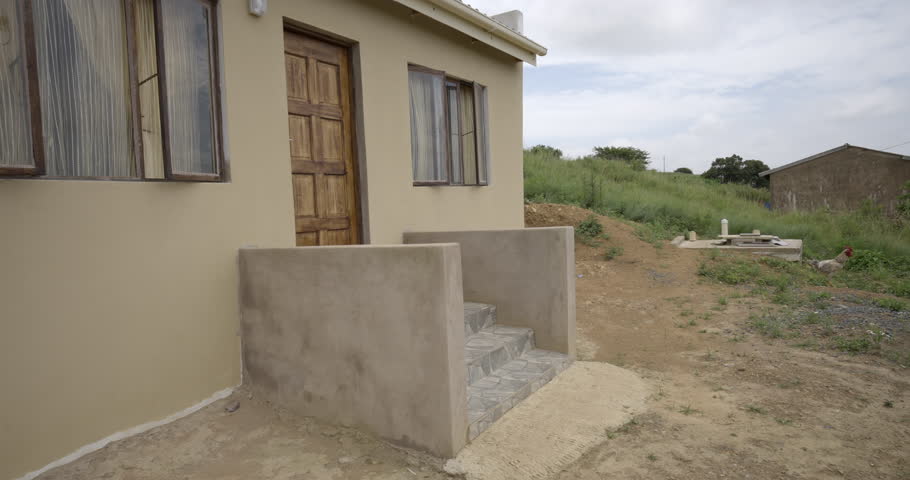 An African woman arrives home in a rural area in Zululand, she  walks up the steps of her new house, opens the door and goes inside.