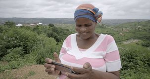 Close up of a black African woman laughing while watching a video on her mobile phone in a rural Zululand setting.