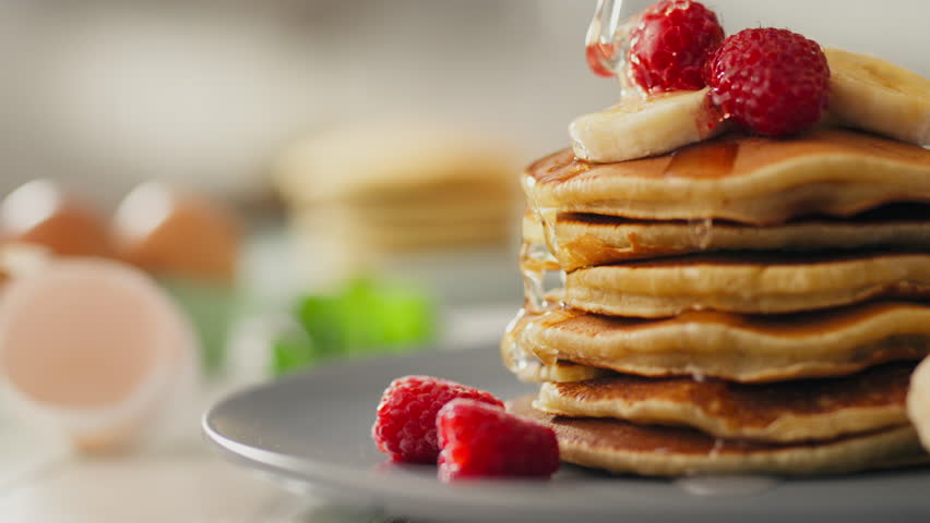 Fruits, Pretty woman pouring maple syrup over prepared pancakes in the kitchen. stay-at-home parent adds maple syrup to sweet pancakes learns new breakfast recipes, berries Royalty-Free Stock Footage #1108322379