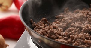 Minced meat is fried in a pan with steam. Close-up. Cooking bolognese sauce. Food preparation in the kitchen. A series of footage to visualize the recipe.