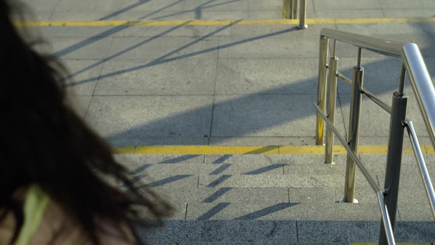 Athletic girl runs down the stairs in the cityscape. Urban location woman on a morning run in the city. High quality 4k footage