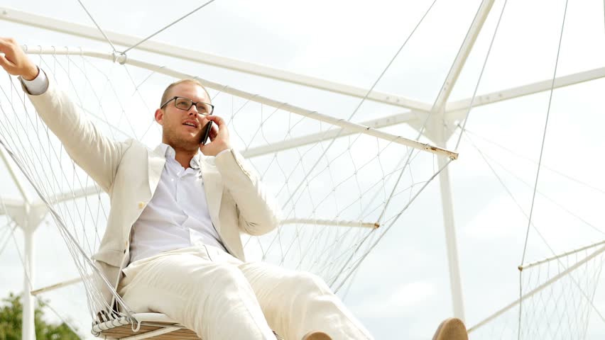Young Man in White Suit Talking on Mobile Phone Outside