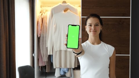 Young woman using smartphone app for sale old unwanted clothes in app. Chroma green screen. High quality 4k footage: stockvideo