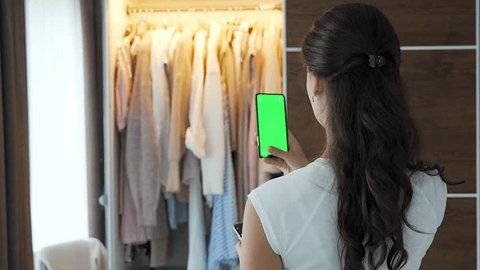 Young woman using smartphone app for sale old unwanted clothes in app. Chroma green screen. High quality 4k footage: stockvideo