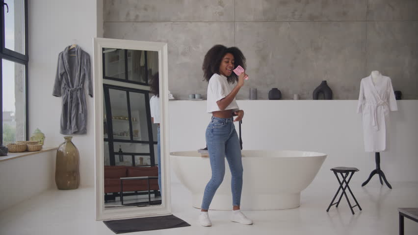 Black Woman Singing in Hairbrush as Microphone. Happy African American female dancing in bathroom. Slow motion. | Shutterstock HD Video #1108332247
