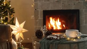 Cozy christmas. Gingerbread cookies and tea cup on table against festive christmas lights and burning fireplace. Winter hygge footage - Powered by Shutterstock - Get 15% off with code: PIKWIZARD15