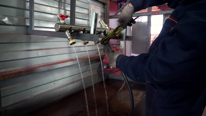 Manufacturing Plant. A Laborer is testing the Pipe that is Leaking. Untightening up the Screws for Fixing the Water Leakage. Picking up the Pipe and Pouring out the Water to Fix the Issue. Production. Royalty-Free Stock Footage #1108333279