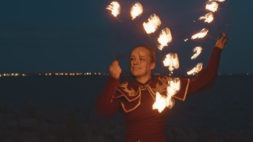 Medium shot of excited Caucasian girl dancing with burning fire fans during night show on beach | Shutterstock HD Video #1108335789