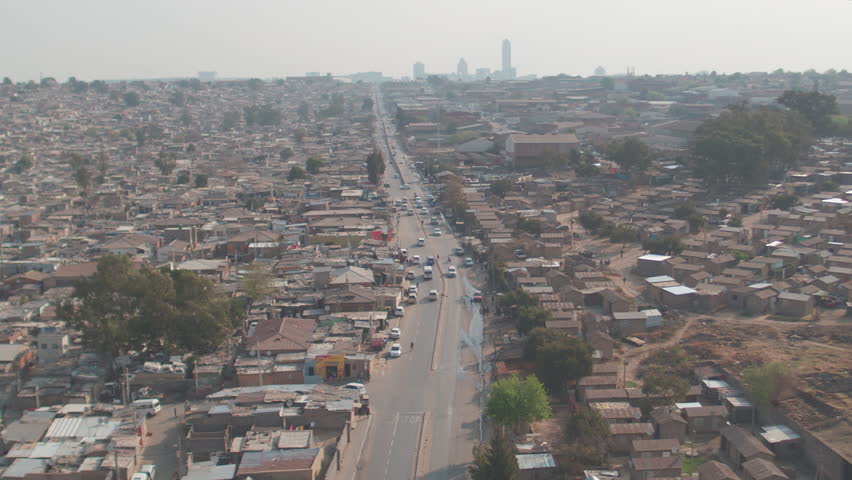 Aerial footage of a low-income neighbourhood in Johannesburg, South Africa, called Alexandra, with high income area, Sandton, in the background