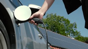 Unrecognizable man plugging in an electric auto or PHEV at photovoltaic charging station. Male hands connect power cable supply to charge EV or electric car on the solar panels background - Powered by Shutterstock - Get 15% off with code: PIKWIZARD15