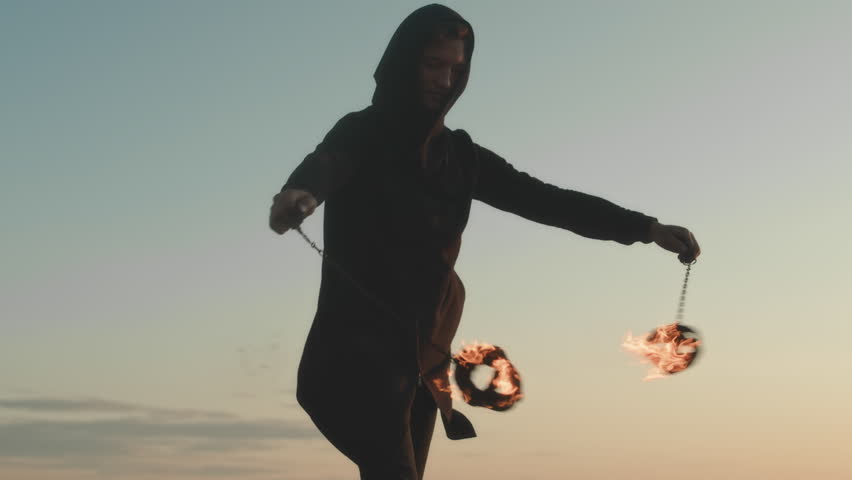 Medium shot of professional performer spinning fire poi while making show outdoors at sunset | Shutterstock HD Video #1108343009