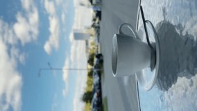 Drinking a cup of hot black coffee on a cafe terrace on a warm sunny day, adding sugar into the mug and stirring it with a spoon. City in the background in bokeh. Lifestyle vertical video.