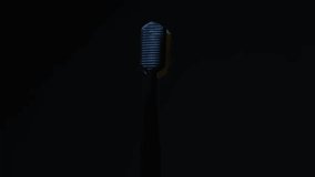 A 360 degree rotating toothbrush with a yellow head. harsh studio light from the side and rear, black background. - Powered by Shutterstock - Get 15% off with code: PIKWIZARD15