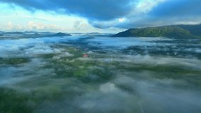 Shrouding the lush tropical forest and verdant plantations in a delicate embrace of ethereal fog. Captured from above by a drone, nature's beauty is unveiled in a mystical sunrise dance. Thailand.
