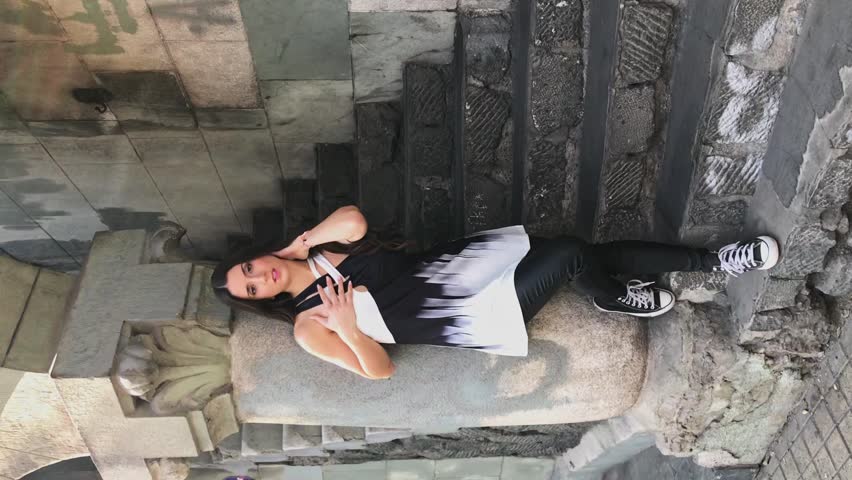 Beauty and charm: beautiful latino brunette model with a black and white fashion look in a urban street making poses and movements in a video and photo shoot