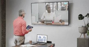 Caucasian businessman on video call with african american female colleague on tv screen. Online connections, business and networking concept.
