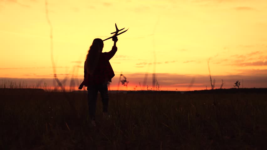 Happy girl runs with toy airplane on field in sunset light. Child play toy airplane. Kid aviator dreams of flying and becoming pilot. Little girl child wants to become pilot and astronaut. Slow motion | Shutterstock HD Video #1108349483