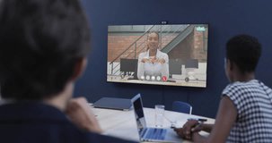 Diverse business people on video call with african american female colleague on tv screen. Online connections, business and networking concept.