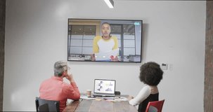 Diverse business people on video call with african american male colleaguge on tv screen. Online connections, business and networking concept.