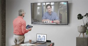 Caucasian businessman on video call with cauacasian male colleague on tv screen. Online connections, business and networking concept.