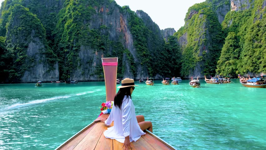 Thai women in front of a Longtail boat at Pileh Lagoon with the green emerald ocean at Koh Phi Phi Thailand, Royalty-Free Stock Footage #1108352037