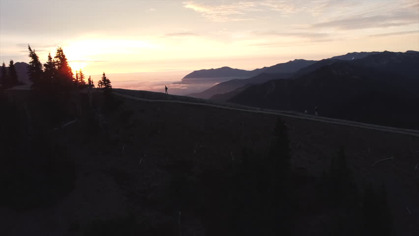 Man Walking on Mountaintop Overlooking Valley at Sunrise in Olympic National Park, Drone Pan Forward, Summer 2021