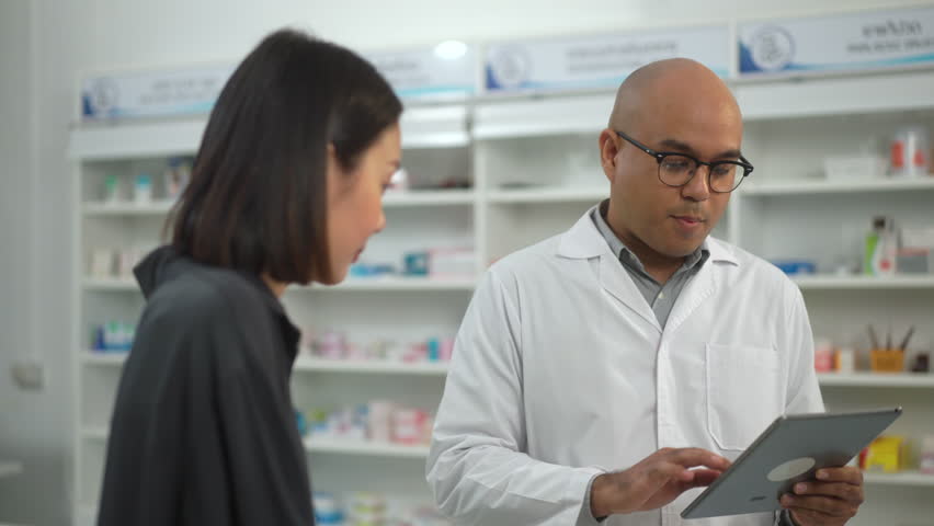 
Professional confident Pharmacist in counseling and explaining on taking prescription medications to patients in a pharmacy. Medical healthcare concept.
