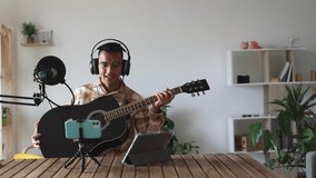young man with guitar recording with microphone, influencer recording live for his audience. tutorial, teacher, online classes