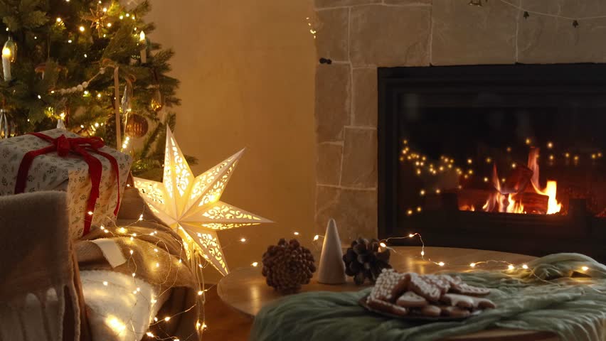 Cozy christmas eve in festive decorated living room. Stylish gifts and gingerbread cookies on table against christmas tree with lights and burning fireplace. Winter hygge footage Royalty-Free Stock Footage #1108362255