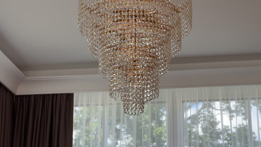 Closeup of a modern luxurious luxury ceiling lamp crystal chandelier handing from the white ceiling of modern interior decor golden gold details Estonian Estonia Europe decoration European style 