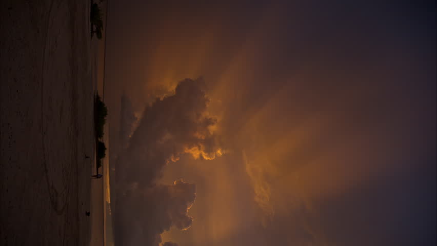 Vertical panning shot of a heavenly sunset in Cancun Mexico with streaks of light coming out of the clouds