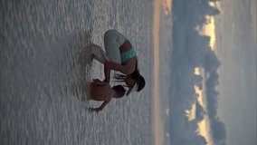 Vertical video in slow motion of a little latin boy sitting in the water with her mother kissing him enjoying the moment on a warm afternoon in Canun Mexico