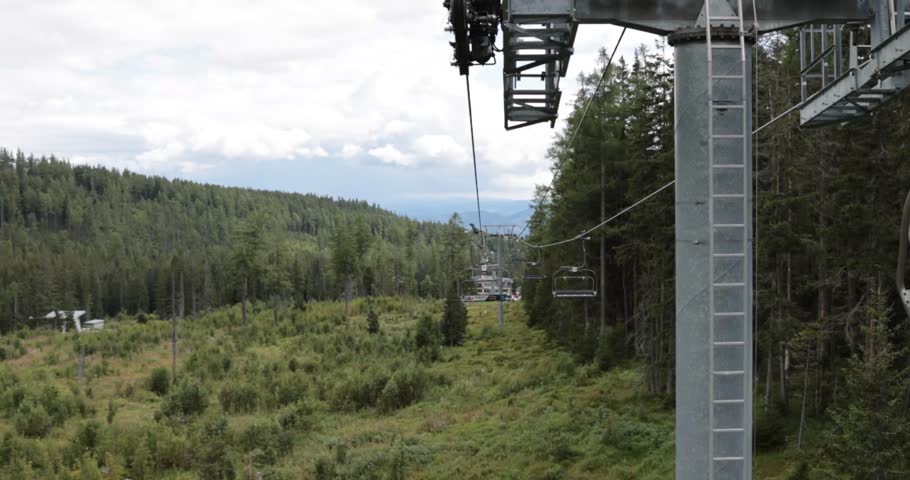 Taking a ride on mountin cableway in beAutiful nature summer. Wedding couple sitting and waving. Groom and Bride in dress. Big mountain in behind.