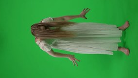 Full-size vertical green screen, chroma key video of a posessed female, woman figure, ghost, poltergeist, zombie moving in an abrupt, convulsive manner. Hair is covering her face. Chroma key.