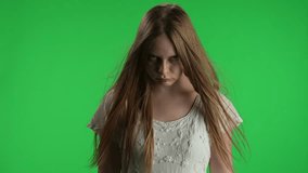 Medium green screen, chroma key video of a posessed female, woman figure, ghost, poltergeist, zombie raising, pulling out a knife, looking at the camera. The wind blows her hair. Chroma key.