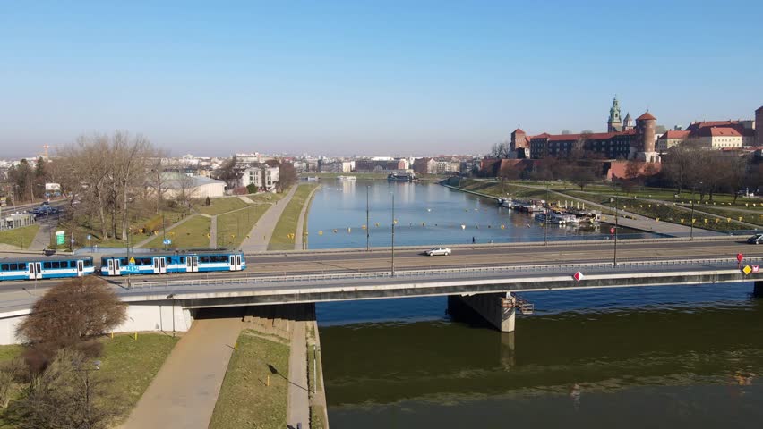 Parallel drone shot of a subway train passing over a bridge in Krakow, Poland