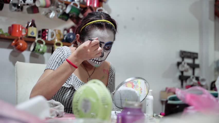 A young Hispanic woman is putting on day of the dead makeup at home Royalty-Free Stock Footage #1108376959