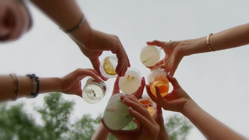 People toast drinking . Low angle view of friends clinking glasses with colorful cocktails. Slow motion - Powered by Shutterstock - Get 15% off with code: PIKWIZARD15