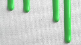 Pale green liquid drops of paint color flow down on white canvas. Abstract art. Green paint dripping on the white wall with copy space